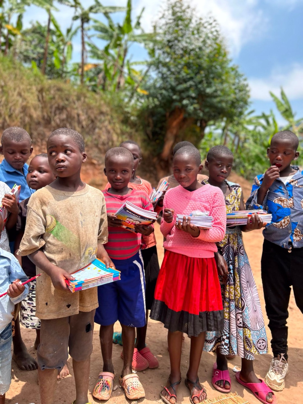 A group of children standing together, each holding new exercise books
