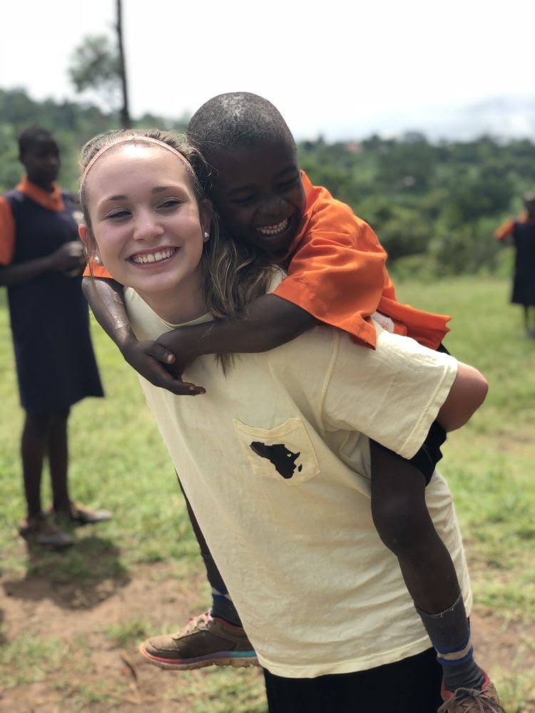 A volunteer giving a laughing boy a piggyback ride